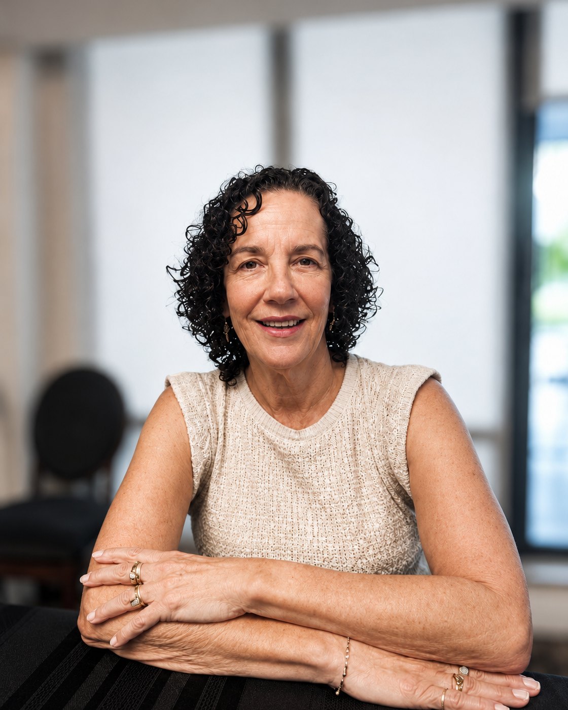 Marsha Gallinger seated with arms gently crossed, smiling